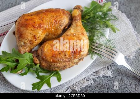 Baked chicken drumstick on a plate with herbs. Stock Photo