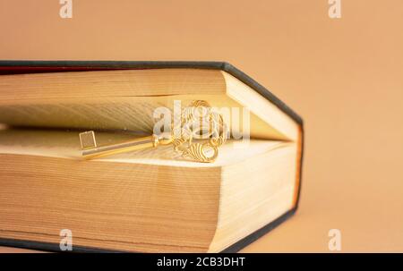 A old beautiful key with magic light lays between the pages of old book. Stock Photo