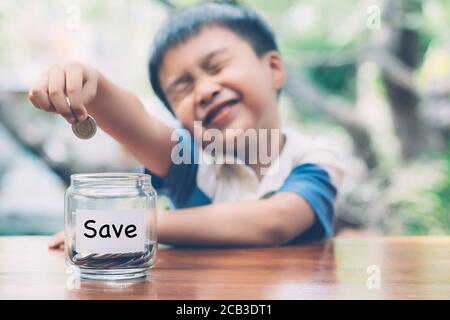 Happy asian children saving money putting coin in glass for wealth and growth of earning in future, finance and investment for success, boy planning a Stock Photo
