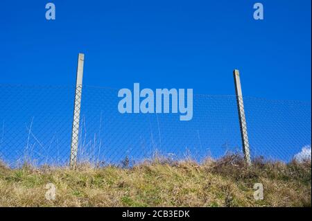 Wire netting as barrier. Protection against entering into territory of restricted area. Clear blue sky in the background Stock Photo