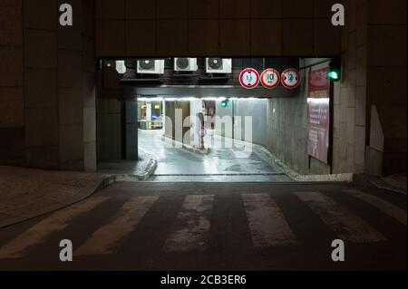 Entrance to underground car park at night. Outdoor area is dark, carpark is lit by artificial light. Stock Photo