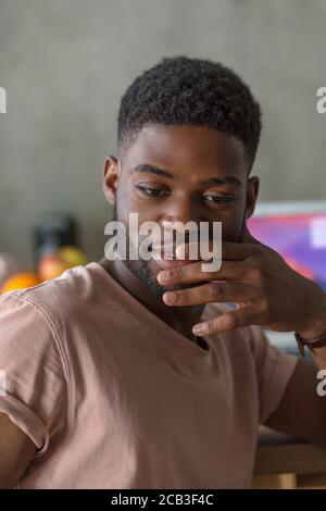 Portrait of a young pleasant looking african american guy in casual wear, who is looking away with pensive thoughtful expression Stock Photo