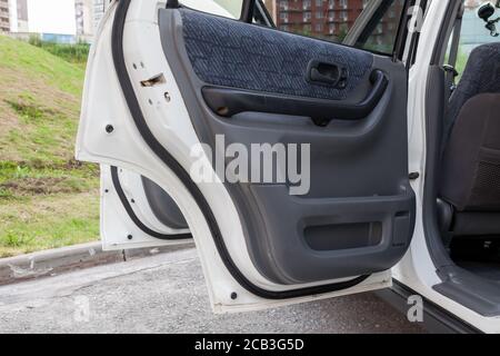 The open side doors of a white Japanese SUV in the parking lot on a summer afternoon from the inside with gray panels and textile accents. Stock Photo