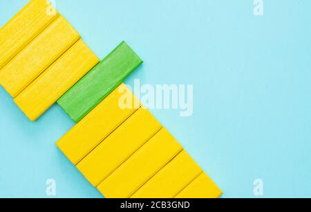 Yellow and green block of jenga block on blue background. Out of the box thinking, Be different concept.  Stock Photo