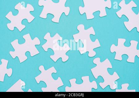 White puzzle pieces scattered on a blue background Stock Photo