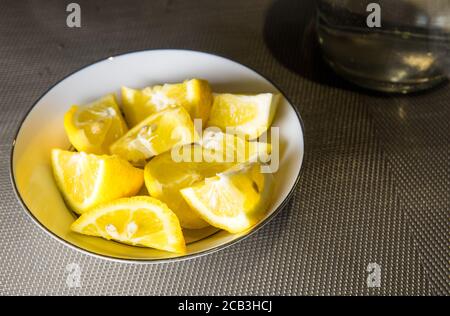 Sliced lemon in a bowl served as an accompaniment for a meal or to add as a cocktail. Cooling in summer and adds alkalinity Stock Photo