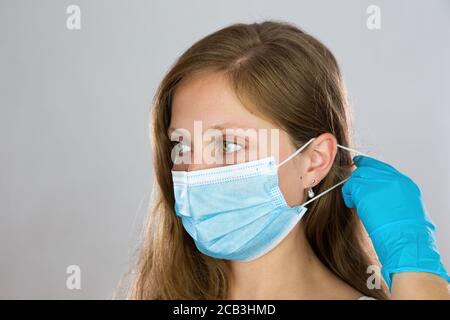 Young woman putting on face mask with white background. Stock Photo
