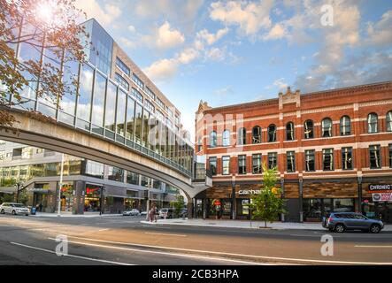 Pedestrians cross the street under the enclosed pedestrian bridge in the shopping and office commercial downtown district of Spokane, Washington. Stock Photo
