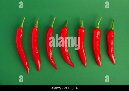 A line of red hot chili peppers on a green background Stock Photo