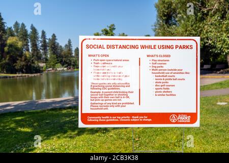 A city park sign in Spokane Washington's public Manito Park offer social distancing information and guidelines for health in Spokane, Washington. Stock Photo
