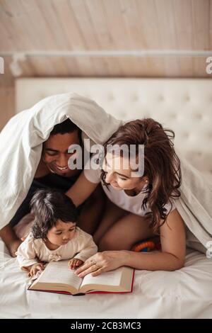 gorgeous couple concentrated on reading a novel, favourite write, daily routine, lifestyle, parents laughing at funny information in the book Stock Photo