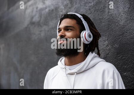 Picture of a concentrated young man walking outdoors while listening music with headphones