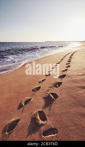 Footprints on a tropical beach at sunset, color toned picture, Sri Lanka. Stock Photo