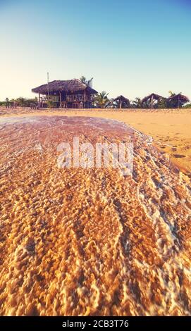 Wooden bar on a tropical beach at sunset, selective focus on hut, summer vacation concept, color toning applied. Stock Photo