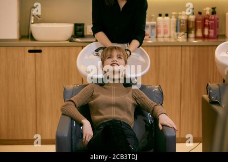 young beautiful woman dyeing hair in modern beauty saloon, professional hairdresser wash and dye woman's hair Stock Photo