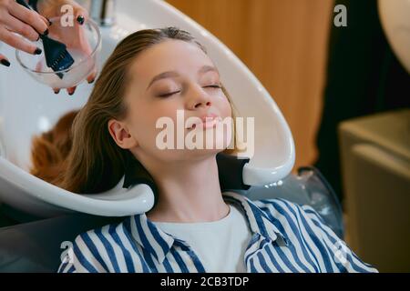 young beautiful woman dyeing hair in modern beauty saloon, professional hairdresser wash and dye woman's hair Stock Photo