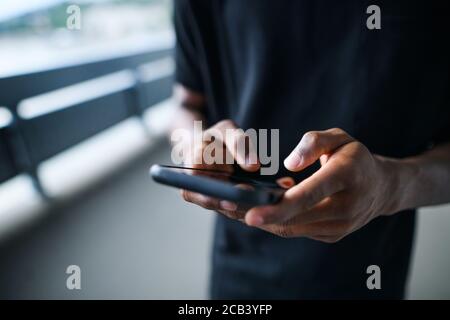 Unrecognizable black man outdoors in city, using smartphone. Stock Photo