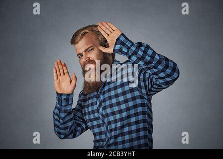 Bearded man scared with shocked facial expression trying to protect himself from unpleasant situation object thrown at him. Hipster male with beard in Stock Photo
