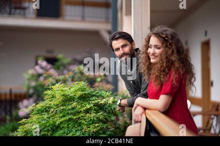 Young couple standing outdoors on hotel balcony on holiday, relaxing. Stock Photo