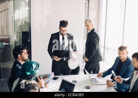 Handome caucasian male manager makes flipchart presentation to diverse colleagues at meeting Stock Photo