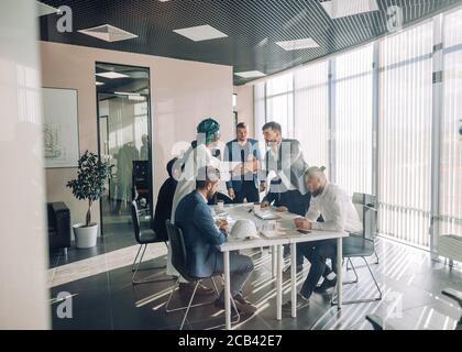Multi-ethnic group of business partners of various ages and ethnicities gathered for meeting to discuss details of company expansion to the east - vie Stock Photo