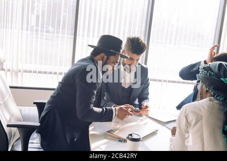 Serious Indian CEO in interacting with multiracial vendors at corporate meeting, explaining development project strategy, proving them to continue coo Stock Photo