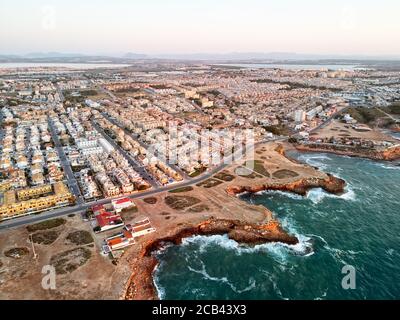 Aerial panoramic photo of Torrevieja cityscape, rocky coastline Mediterranean Sea during sunrise, Salt lake or Las Salinas, image view from above. Pro Stock Photo