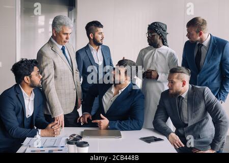 Formal meeting of several multi-ethnic male colleagues gathered in executive s office to discuss new ideas Stock Photo