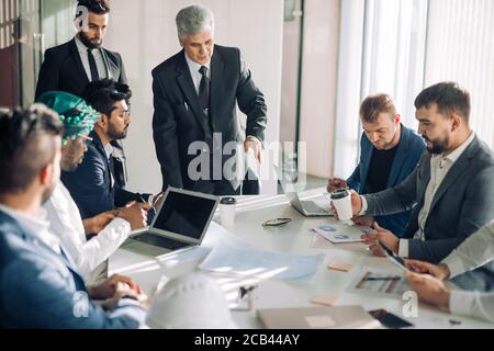 Collaborative process of multicultural professional financial or marketing managers during brainstorming meeting in office, headed by mature Senior He Stock Photo