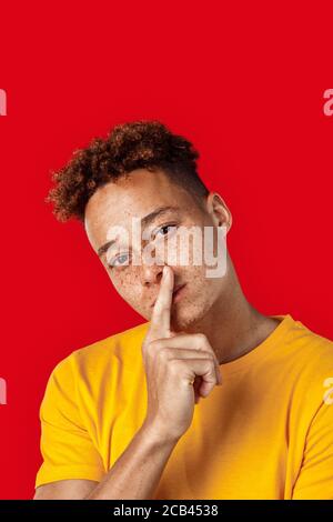 Freestyle. Mulatto freckled guy in yellow t-shirt standing isolated on dark pink Stock Photo