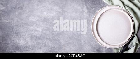 Banner with plates, black cutlery and linen napkin on stone table. Setting table with copy space in natural colours, top view. Stock Photo