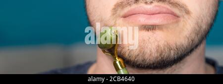 Bearded man is using jade face roller Stock Photo