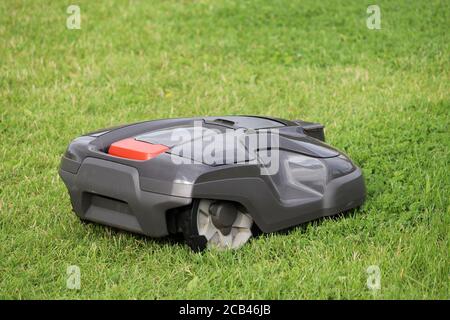 Robotic lawn mower mowing grass on a meadow. Automower in summer park