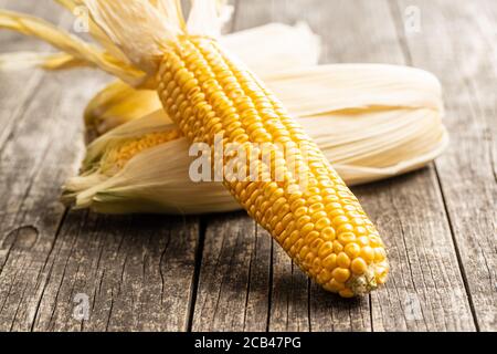 Uncooked corn cob on wooden table. Stock Photo