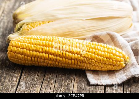 Uncooked corn cob on wooden table. Stock Photo