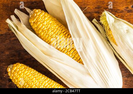 Uncooked corn cob on wooden table. Top view. Stock Photo