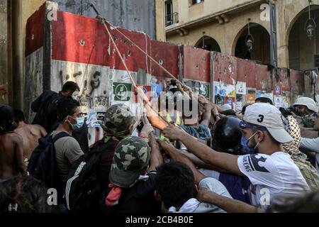 Beirut, Lebanon. 10th Aug, 2020. Anti-government activists try to put down the concrete block which is closing the road that leads to the house of the parliament during clashes with riot police in Beirut's downtown. The Lebanese government resigned following the massive Beirut port explosion of 04 August which killed at least 158 people, wounded 6000 and displaced some 250,000 to 300,000. Credit: Marwan Naamani/dpa/Alamy Live News Stock Photo