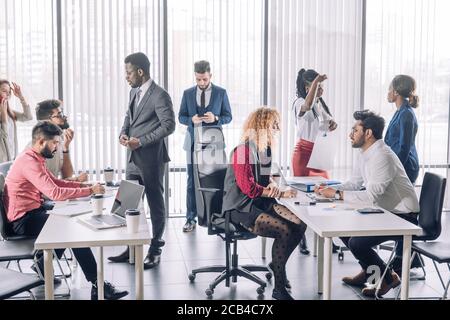 Young business team having a break while participating in a brainstorming session sitting or walking around and sharing new ideas with colleagues. Stock Photo