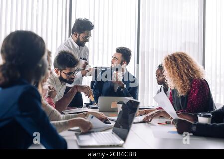 Caucasian businessman takes advice to Indian financial advisor during meeting with his strategic partners at his office Stock Photo