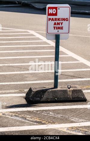 A No Parking Any Time Sign with Zebra Lines in the Background Stock Photo