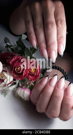 Girl's hands with manicure close-up. Beautiful manicure with beige nails and a black rim. Nail care in a beauty salon. Stock Photo