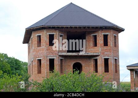 Facade of an unfinished two-story house with no red brick windows