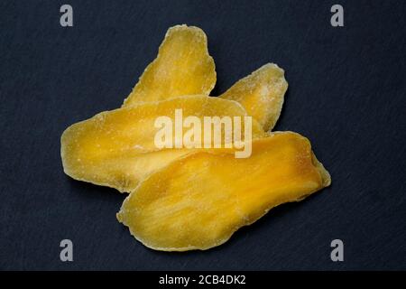 Dried mango without sugar. Natural mango petals on a black board top view. Dried mango pulp, dried fruits, healthy vegetarian snacks. Stock Photo