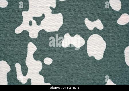 Green background with beige spots. Fabric in beige spots, camouflage. Fabric for sewing military uniform. Stock Photo