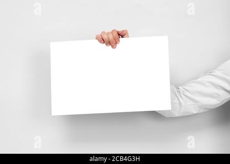 Hand holds from the top white board with copy space on white background. Stock Photo