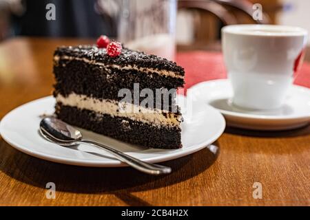 Plate with a slice of delicious chocolate cake decorated with berries on the table, close up Stock Photo