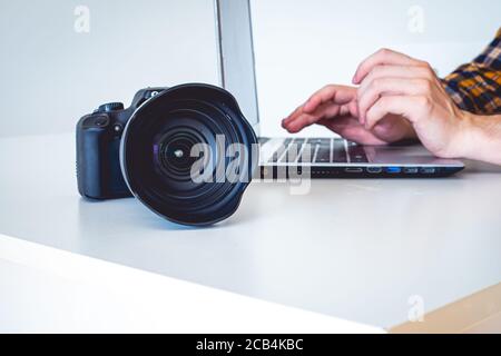 Closeup of a camera with a man working on a laptop on the side Stock Photo