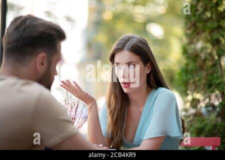 Sad couple sitting in open air cafe, arguing with each other Stock Photo