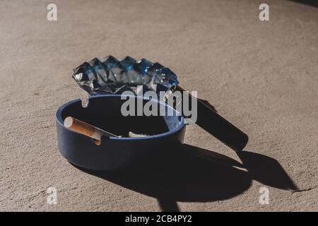 Shot of a cigarette in an ashtray and a cigarette lighter Stock Photo