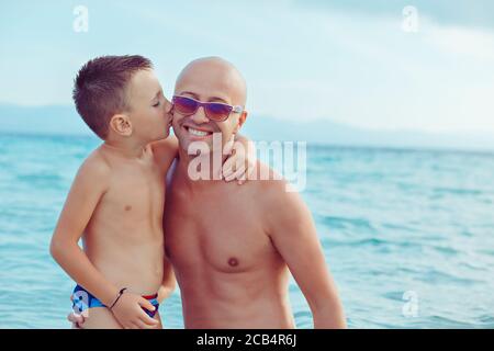 father and child playing in water having a great time. Son giving a kiss to a beloved parent Stock Photo